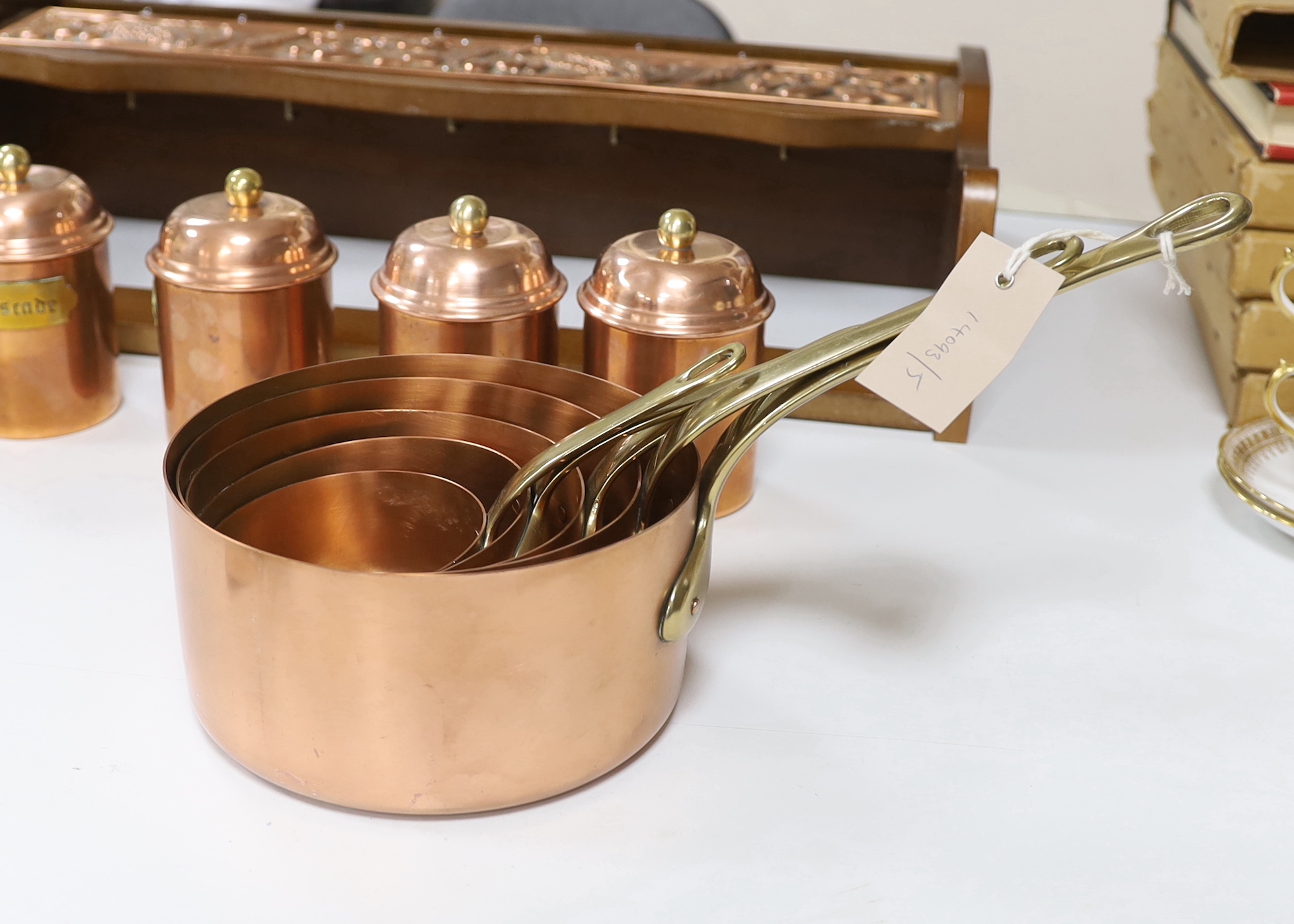 A graduated set of five French copper and brass saucepans and five lidded jars with copper mounted beech hanging rack